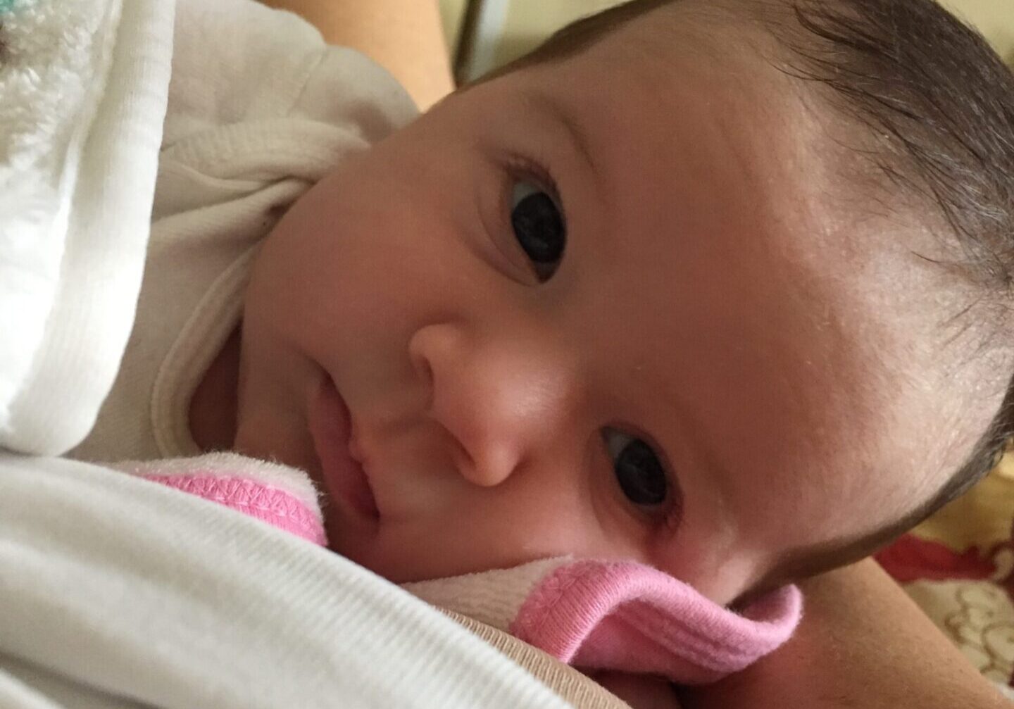 A baby with a pink phone in its mouth.